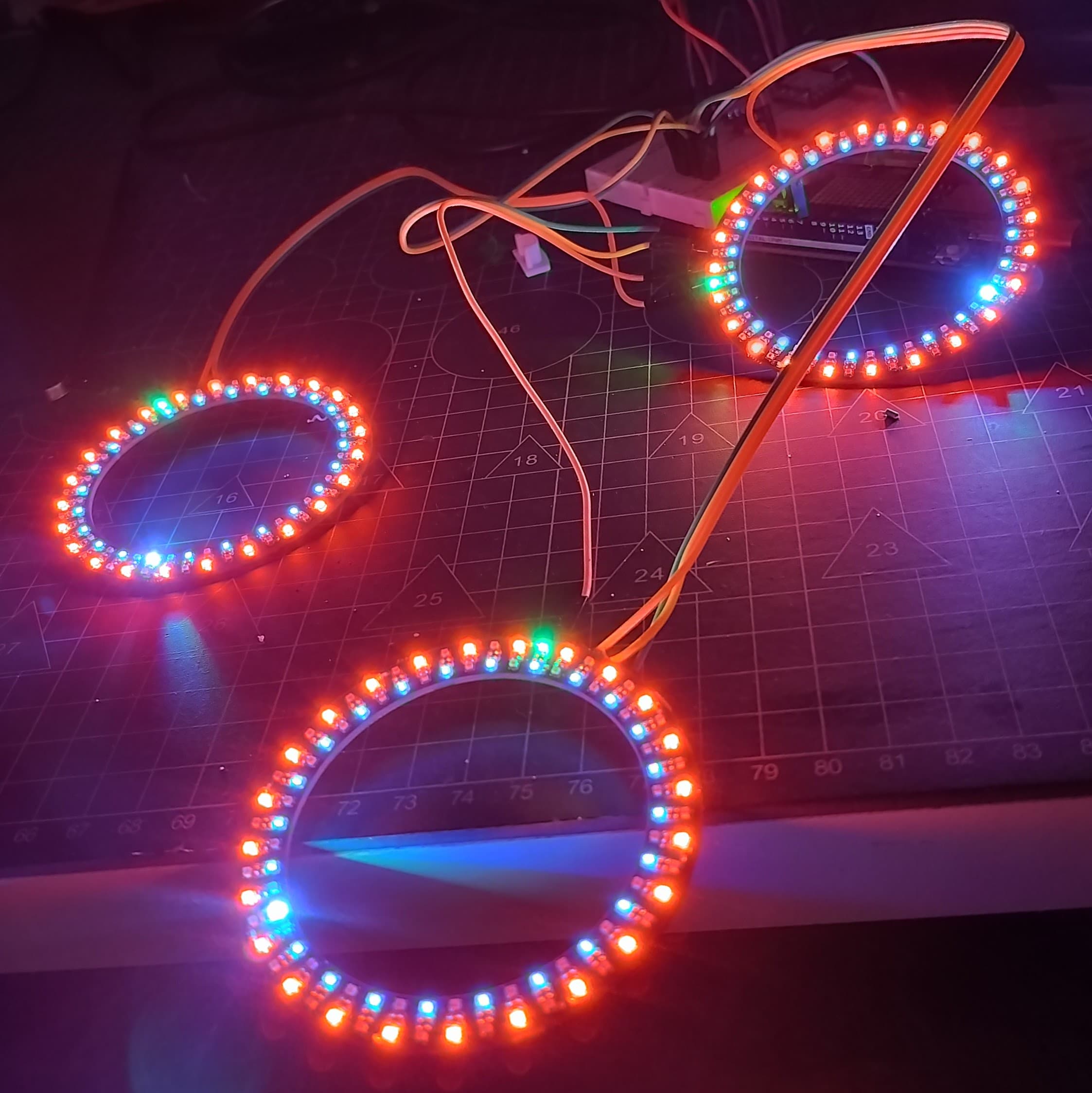 Three daisy-chained NeoRings lit with colorful LEDs